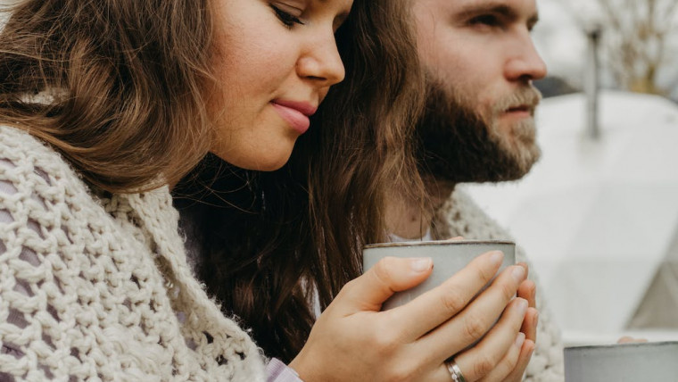 wife and husband in knitted shawl enjoying hot drink